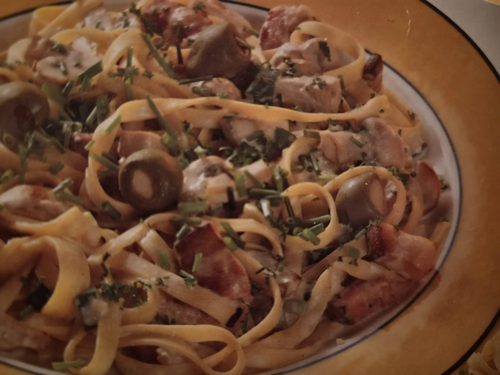 Een bord tagliatelle met champignons, ontbijtspek en bieslook